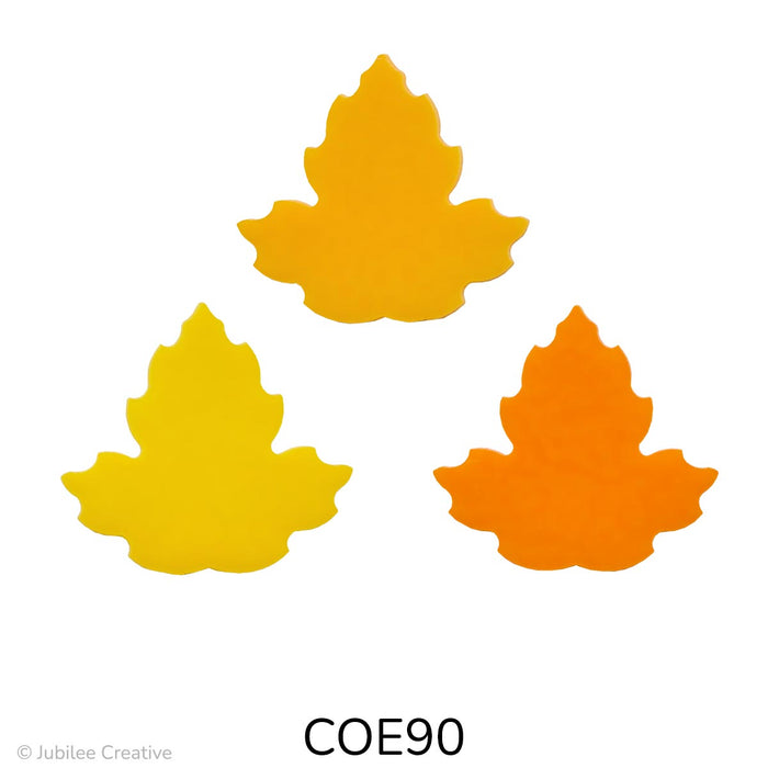 Image shows three glass maple leaves in bold, solid colors: bright yellow, golden orange, and deep orange. Each leaf has a smooth, symmetrical three-lobed shape.