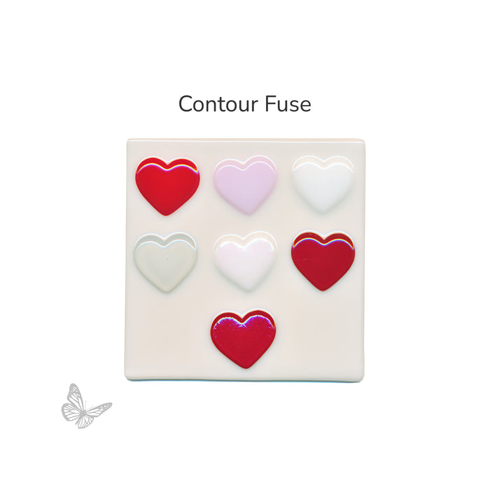 Square block with seven heart shapes contour fused in opaque red, opaque pink, opaque white, clear, translucent red, white iridized, and red translucent iridized on a white background.