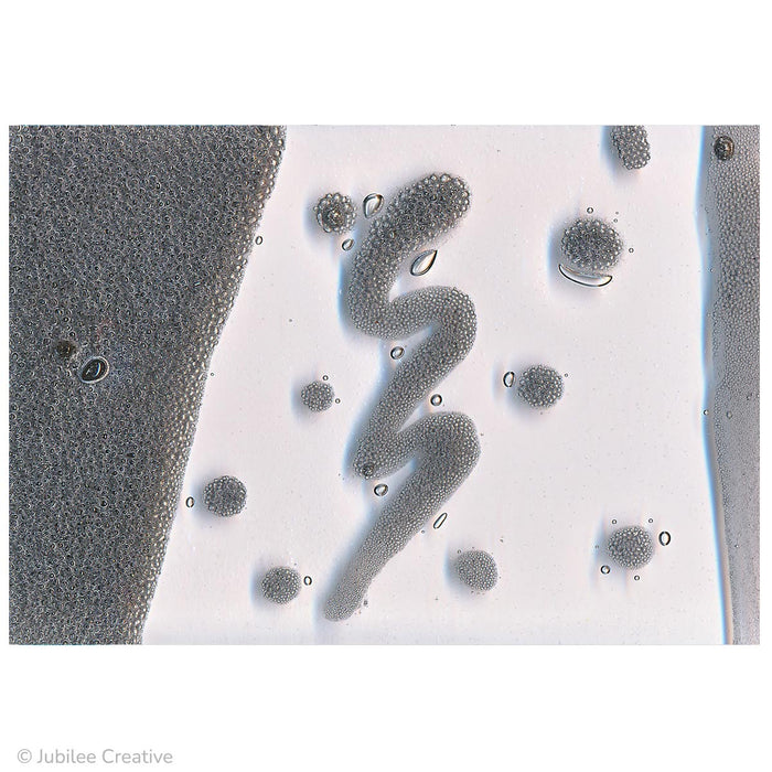 image of grey bubble art paint fused between two pieces of glass. After fusing grey colored bubbles of all sizes are shown.