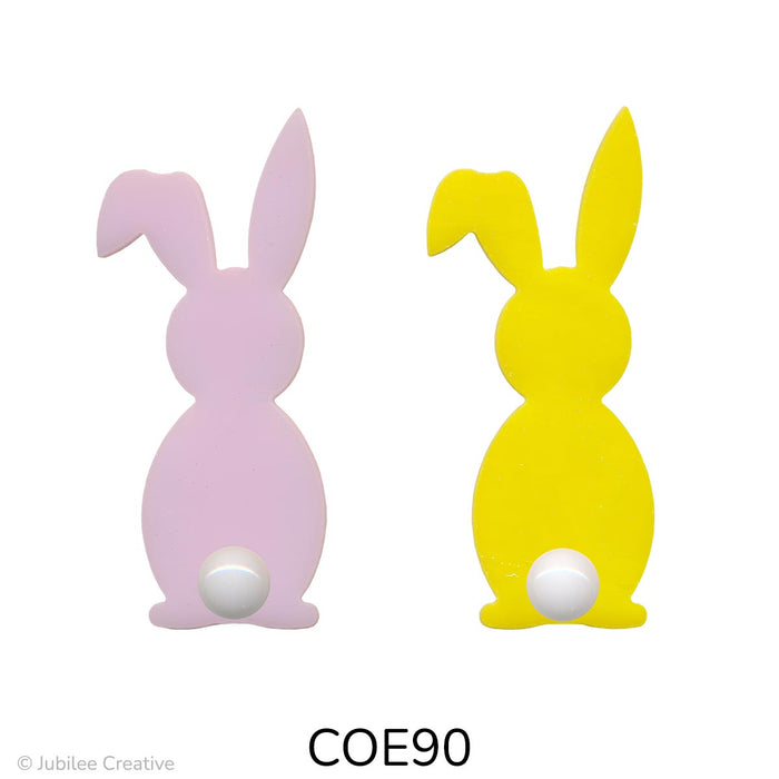 image of two fusible precut glass bunnies with a cotton ball for a tail. One bunny is opaque pink and the other is opaque yellow - COE90