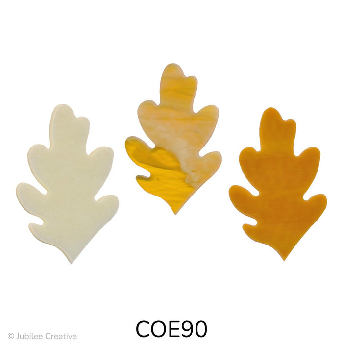 Image shows three glass oak leaves in autumn shades. Each leaf has a classic lobed shape and varies in color, including creamy beige, golden amber, and rich brown swirls.