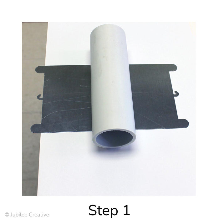 image of Step 1. Place the mold flat on a protected work surface so that the feet hang off and make sure the mold is flush with the edge of the work surface. Center the PVC pipe on the mold making sure it is parallel to the edge of your work surface.